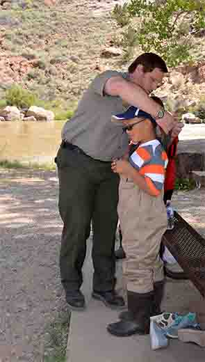 Abiquiu Lake project manager John Mueller assists one of the students with his waders before they headed to the river, Sept. 6, 2017.